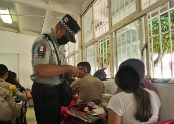 Un elemento de la guardia nacional inspecciona a una de las alumnas de la secundaria en Ixtlán.