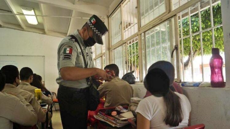 Un elemento de la guardia nacional inspecciona a una de las alumnas de la secundaria en Ixtlán.